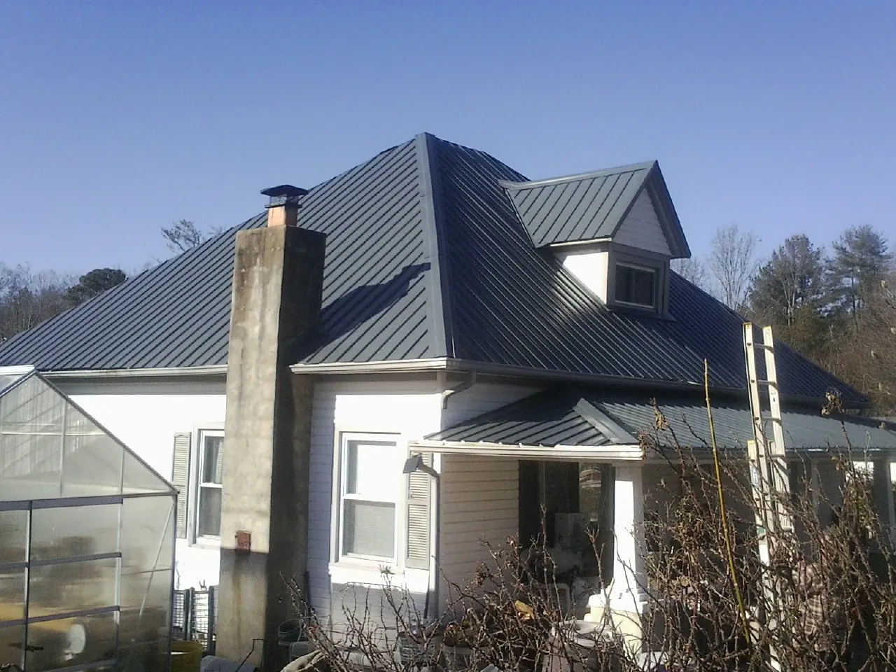 Dark blue standing seam metal roof on a white farmhouse with dormer — Slate & Tile Roof Repair by Roofing Brothers in Rainier