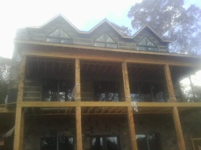 Dormers and porch framing on a large log home under construction — Roof Coating work by our crew in Rainier