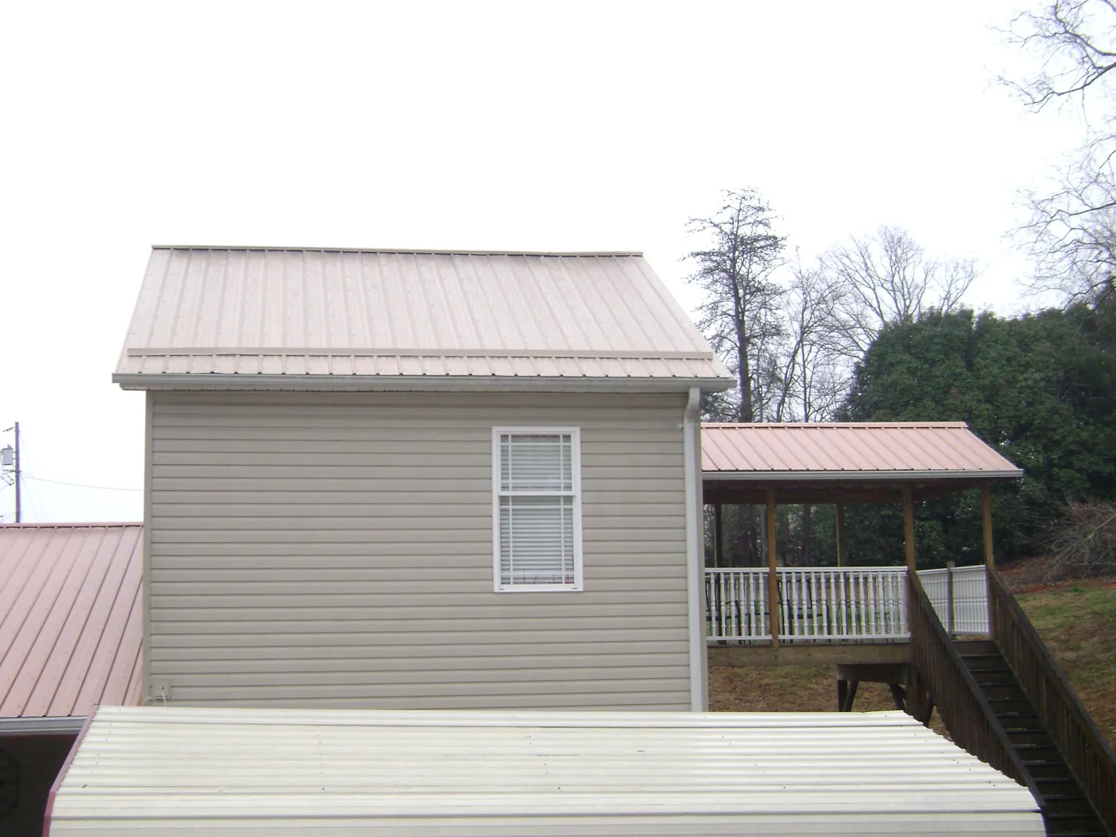 Tan metal roofs on a two story addition and attached porch, from a Roof Replacement job in Rainier
